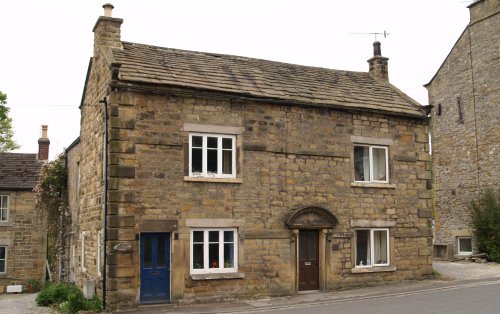 Fern Cottage, a solid built house with a fine carved arch over the front door, on the main street of Eyam.