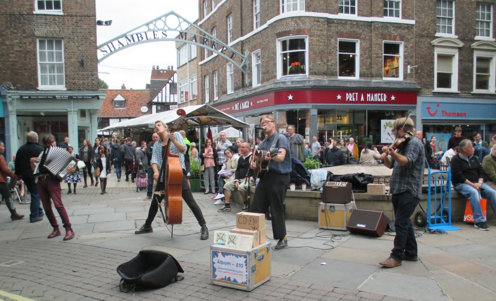 The Hyde Family Jam band performing their music at Jubbergate entrance to Newgate market (Shambles Market) on Parliament Street, York, England