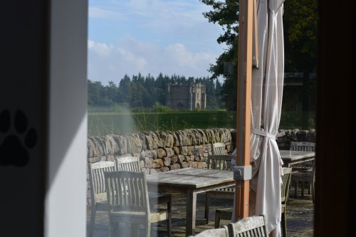 view of Fountain's Abbey tower from inside the cafe and outside seating in the sun