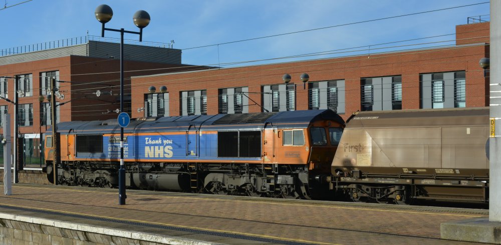 Class 66/7 diesel electric locomotive Class 67 66731 CAPTAIN TOM MOORE (Thank You NHS) passing south through York station with 0917 Tyne Coal Terminal to Drax power station freight train of biomass wagons