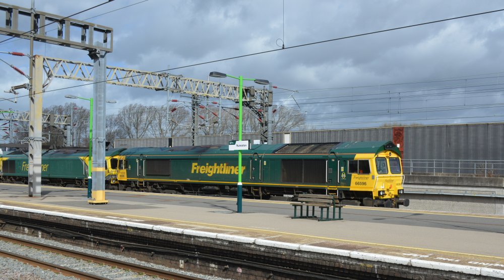 A pair of Class 66 diesel freight locomotives (66596 and 66414) head south through Nuneaton station with a Crewe Basford Hall S.S.M to Southampton MCT intermodal freight train (March 2023).